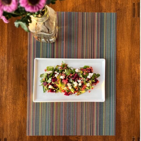 A plate with a Beet and Farro Salad, adorned with flowers in a vase.